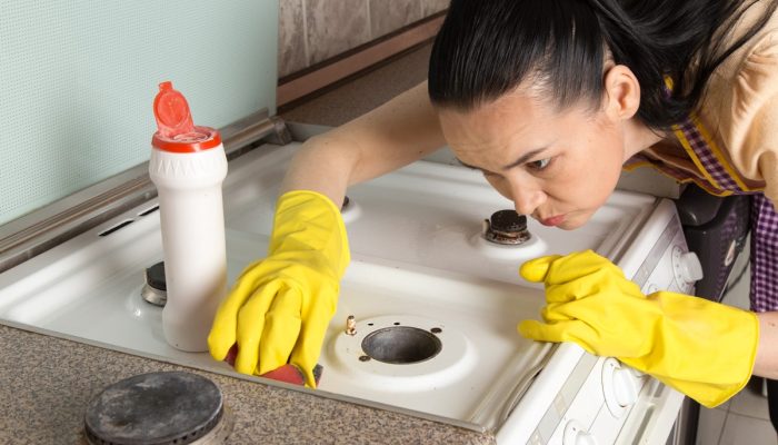 young-housewife-with-yellow-gloves-cleaning-gas-stove.jpg